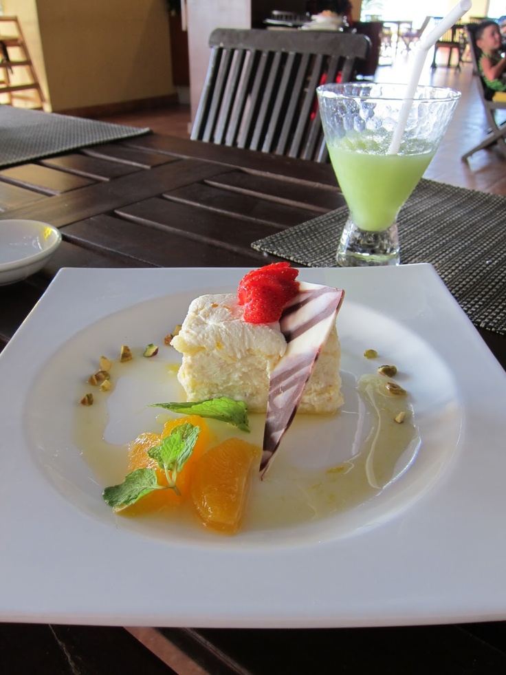 a white plate topped with dessert next to a glass filled with green liquid and fruit