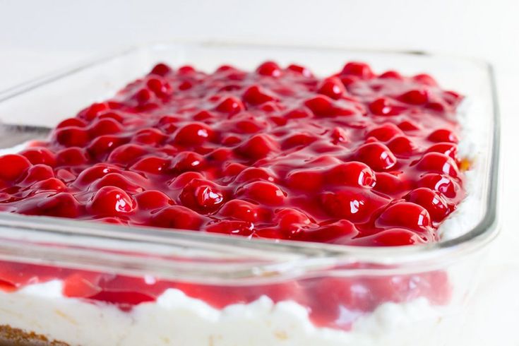 a dessert dish with cherries on top in a glass casserole dish, ready to be eaten