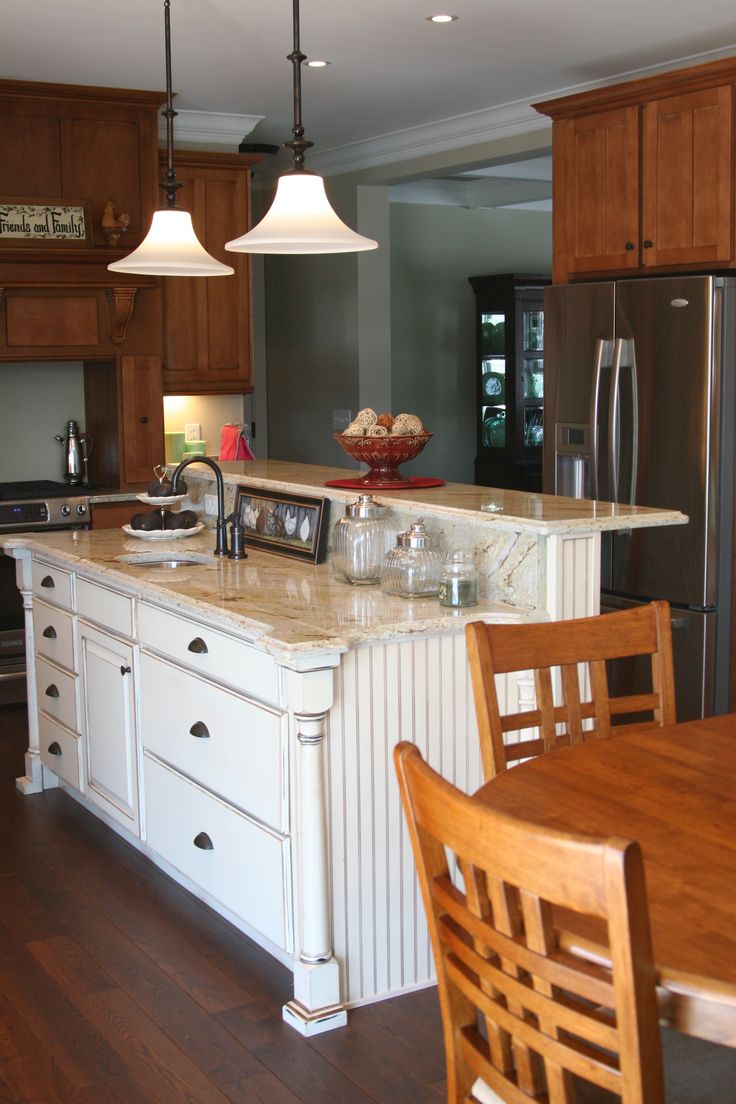 a kitchen with an island, refrigerator and dining room table in it's center