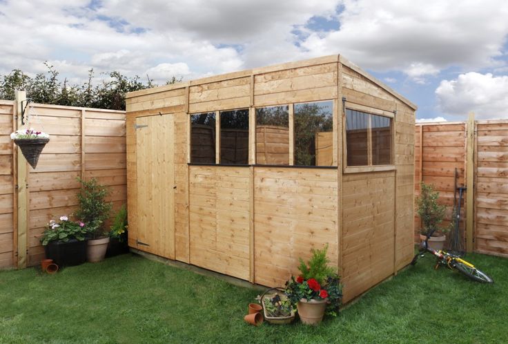 a wooden shed sitting in the middle of a yard