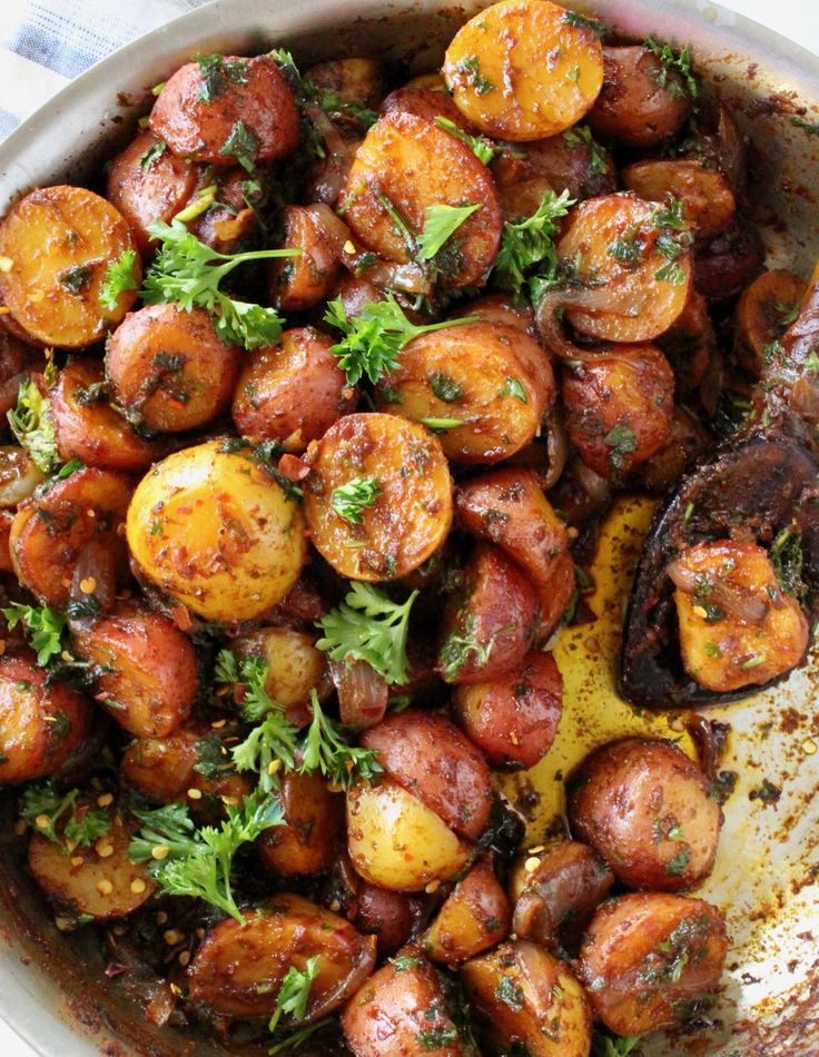 potatoes with parsley in a pan on a white and blue table cloth, ready to be eaten