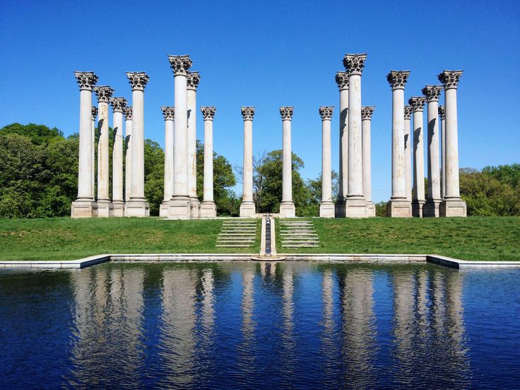 an image of a lake with columns in the back ground and grass on the other side