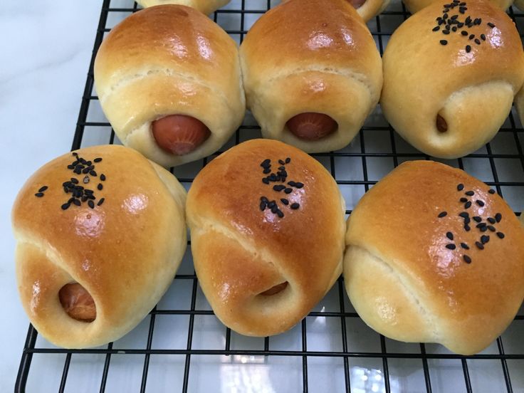 six hot dogs wrapped in bread on a cooling rack