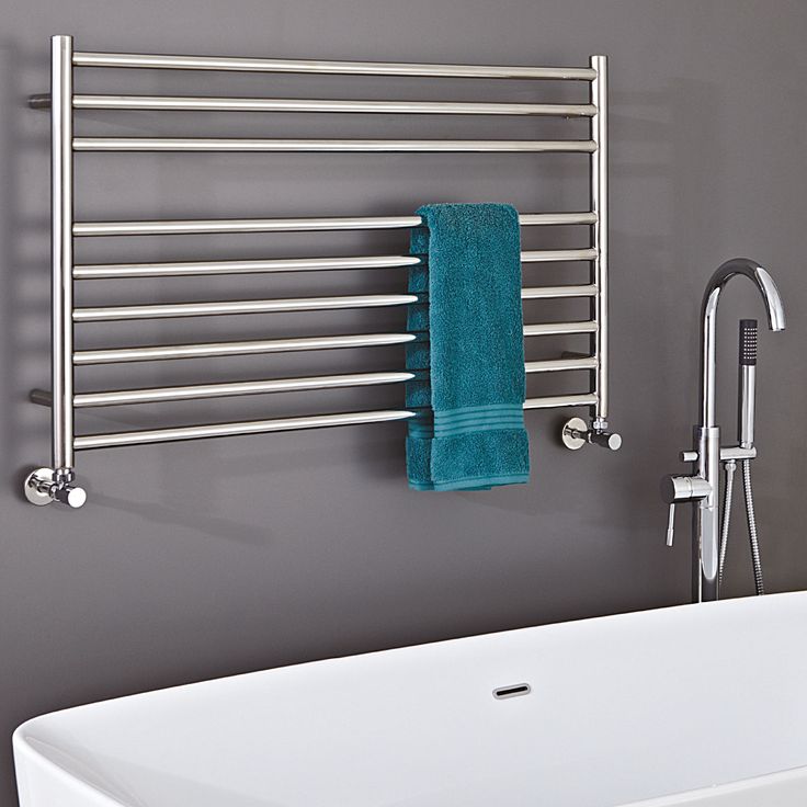 a bathroom with a tub, towel rack and bathtub next to it in front of a gray wall