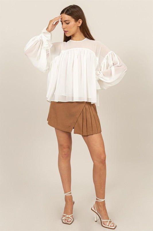 ELEVATE YOUR STYLE WITH THIS FLOWY LONG SLEEVE BLOUSE. FEATURING DRAMATIC GATHERED CUFFS AND A RELAXED, AIRY FIT, THIS BLOUSE OFFERS BOTH COMFORT AND ELEGANCE. PERFECT FOR A CASUAL DAY OUT OR A SPECIAL OCCASION, ITS UNIQUE DESIGN ADDS A TOUCH OF SOPHISTICATION TO ANY OUTFIT. Spring Blouse With Sheer Sleeves For Layering, Fall Blouse With Sheer Sleeves For Layering, Casual White Blouse With Sheer Sleeves, Spring Trendy Blouse With Sheer Sleeves, Trendy Spring Blouse With Sheer Sleeves, Trendy Blouse With Sheer Sleeves For Spring, White Sheer Blouse For Fall, Trendy White Sheer Blouse, Fall White Sheer Blouse