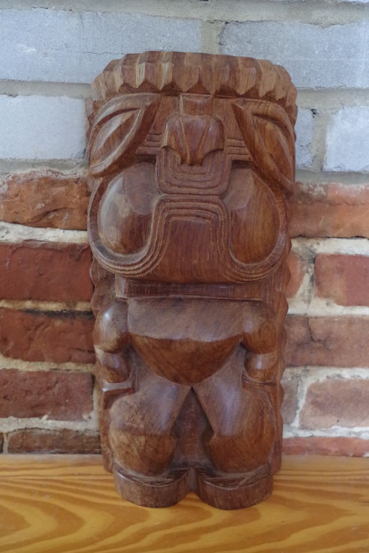 a wooden statue sitting on top of a wooden table next to a brick wall and window