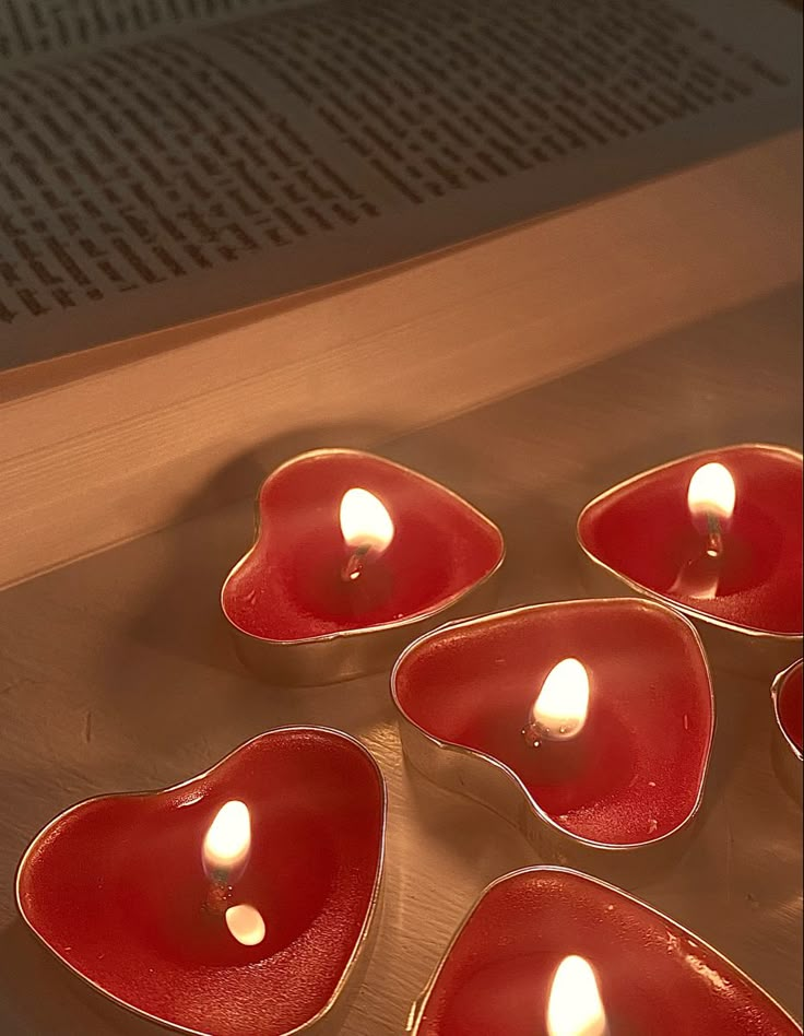 red heart shaped bowls with lit candles in them