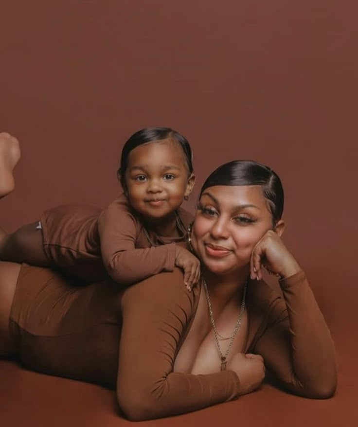 a woman and child laying on the ground posing for a photo with their arms around each other