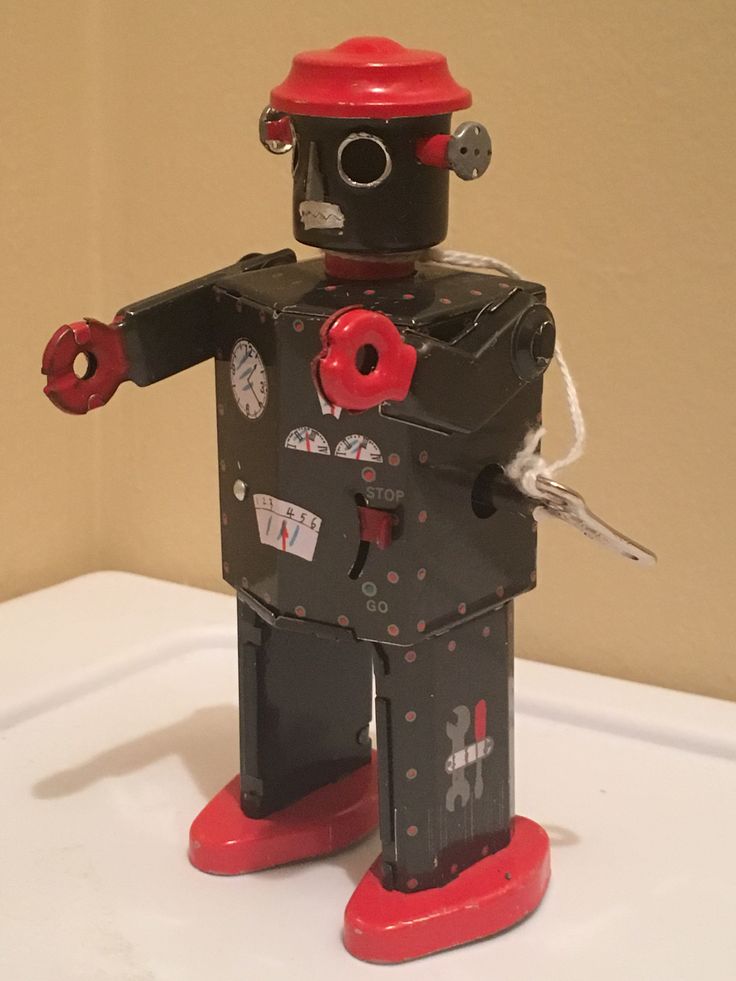 a toy robot is standing on top of a white table with a red hat and scissors