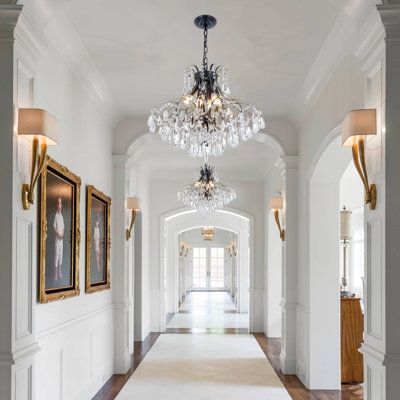 an elegant hallway with chandelier and pictures on the wall in front of it