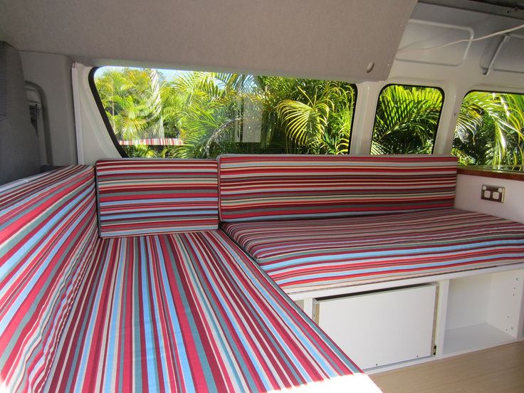 the inside of a camper with colorful striped bedspread and pillows on it