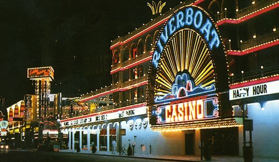 the neon vegas sign is lit up at night in front of hotels and casinos