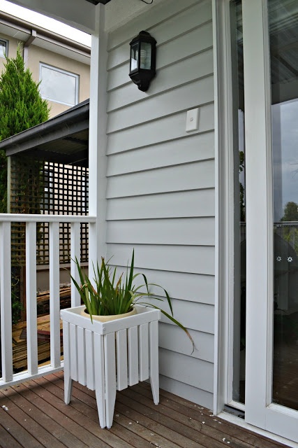 a white planter sitting on top of a wooden deck next to a door way