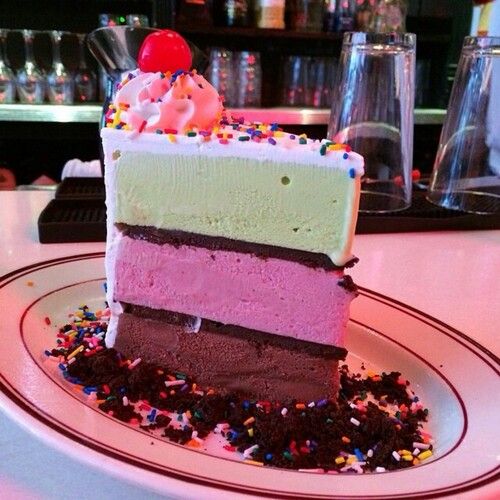 a slice of cake with sprinkles on it sitting on a plate in front of a bar