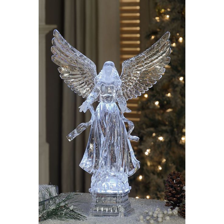 an angel figurine sitting on top of a table next to a christmas tree