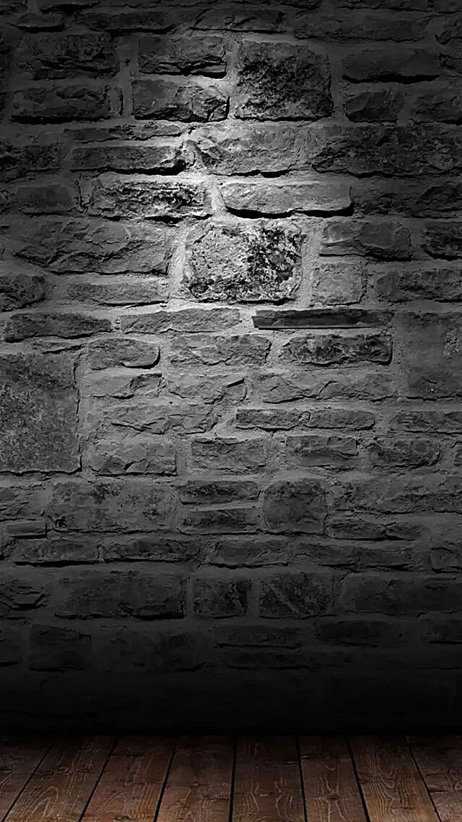 an empty wooden floor in front of a brick wall with light coming from the top