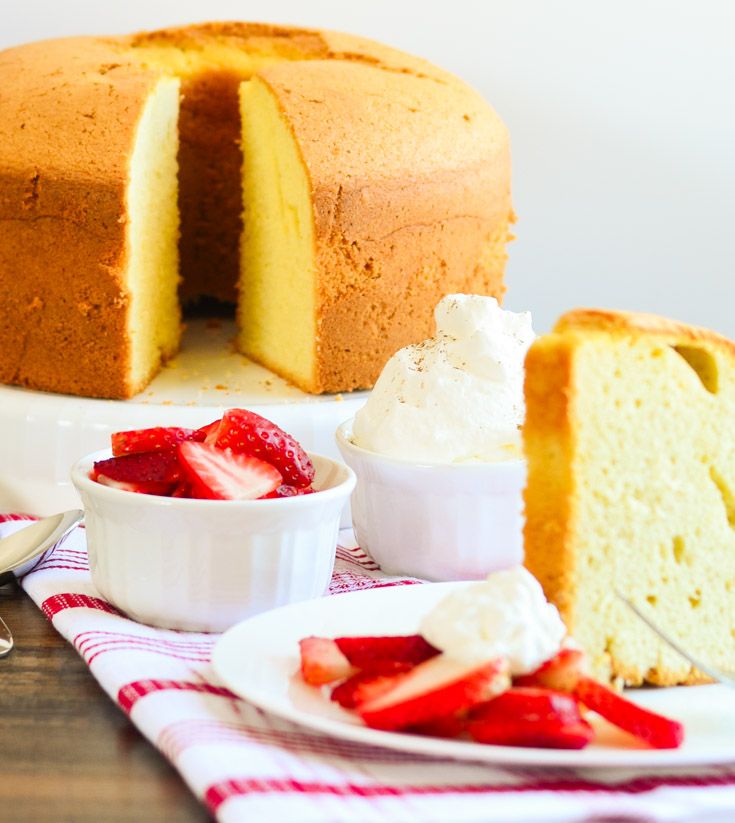 a cake with two slices cut out and strawberries on the plate next to it