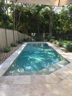 an outdoor swimming pool in the middle of a yard with trees and bushes around it