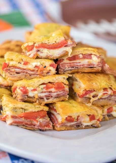 a stack of food sitting on top of a plate covered in cheese and tomato slices