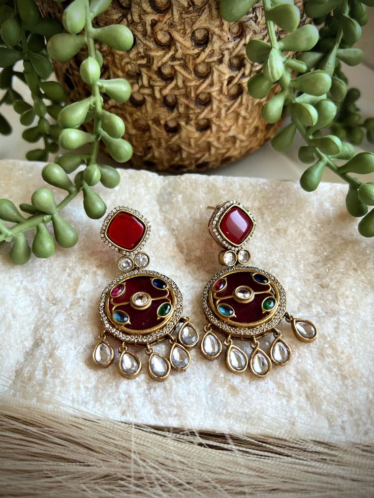 These exquisite earrings are handcrafted with intricate inlay work, featuring vibrant semi-precious stones set in a rich, red background. The intricate design is adorned with glistening crystals and accented with delicate crystal drops, creating a stunning and eye-catching pair of earrings. Crafted with meticulous attention to detail, these earrings are a true work of art. The inlay technique showcases the skill and artistry of the craftsperson, resulting in a unique and timeless piece of jewelry. Whether for a special occasion or as an everyday accessory, these earrings are sure to elevate any outfit and add a touch of elegance. Perfect for those who appreciate exquisite craftsmanship and one-of-a-kind designs. ------------------------------------------------------------------------------ Diwali Multicolor Drop Danglers, Everyday Accessories, Crystal Drop, Keep Jewelry, Jewelry Inspo, Semi Precious Stones, Red Background, Stone Settings, Intricate Design