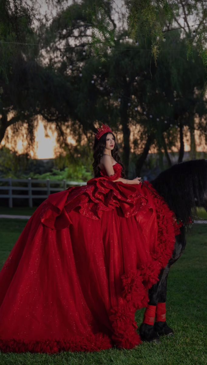 a woman in a red dress sitting on top of a horse