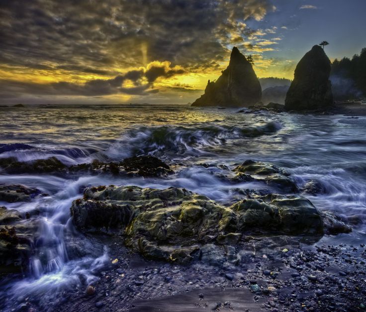 the sun is setting over some rocks in the ocean