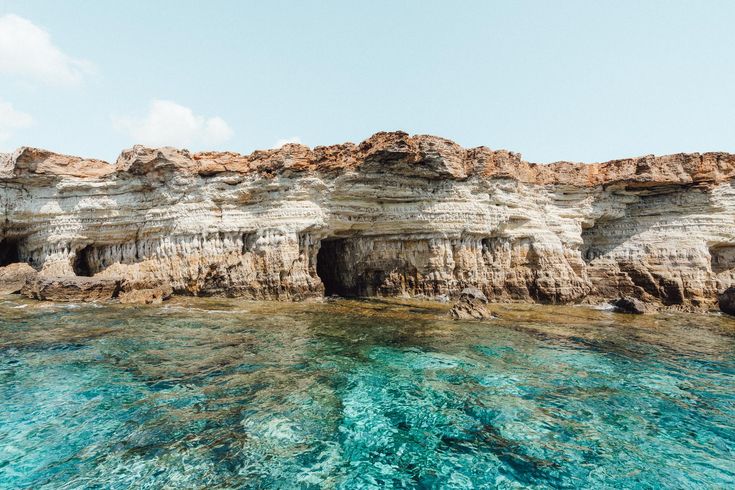 the water is crystal blue and clear with some cliffs in the backgrouds