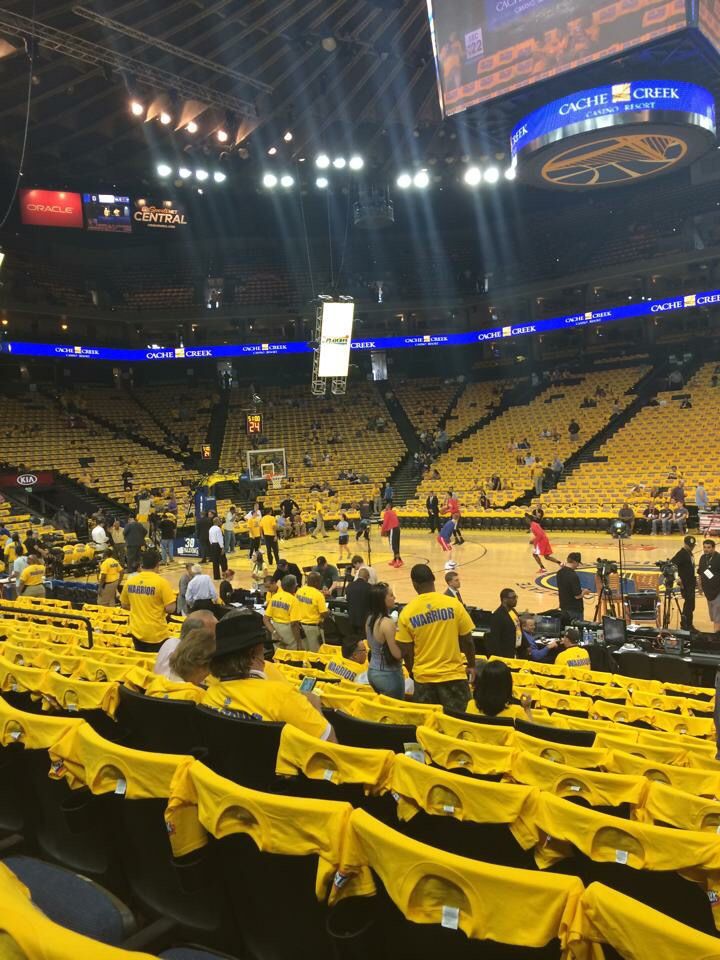 an empty basketball court with yellow chairs and people in the stands looking at something on the floor