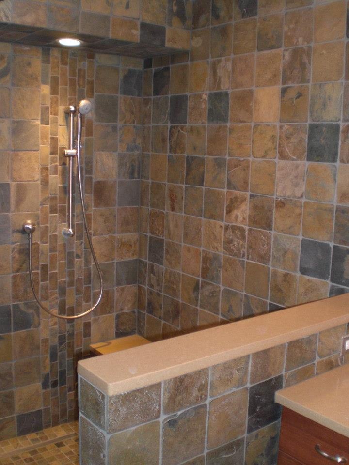 a walk in shower sitting next to a sink under a faucet mounted on a wall