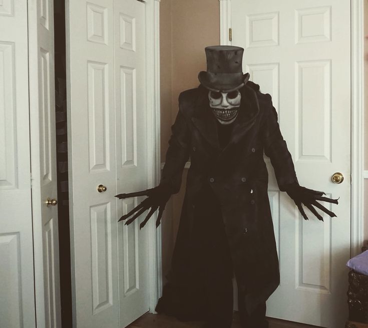 a skeleton dressed up in a top hat and trench coat standing next to two doors