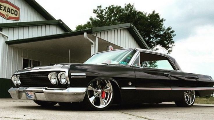 an old black car parked in front of a building