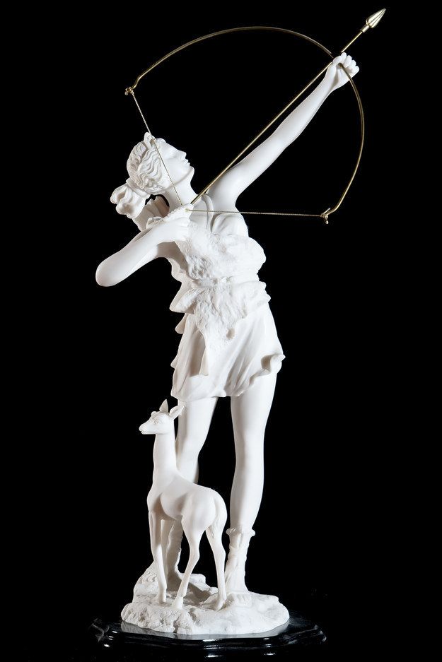 a white statue with a bow and arrow on it's head holding a dog