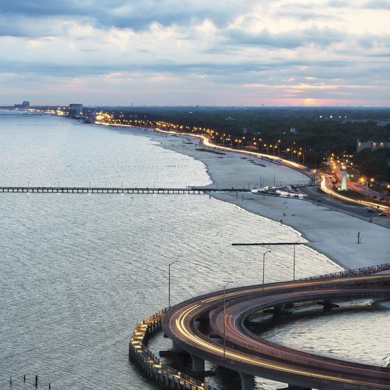 an aerial view of a highway and the ocean at dusk with cars driving on it