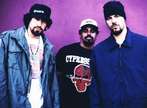 three men standing next to each other in front of a purple wall and wearing beanies