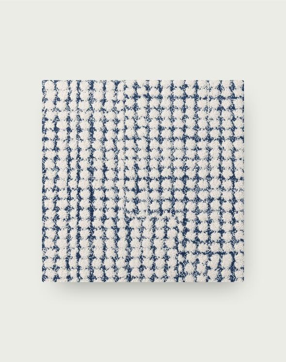 a blue and white checkered napkin on top of a gray surface with an embroidered pattern