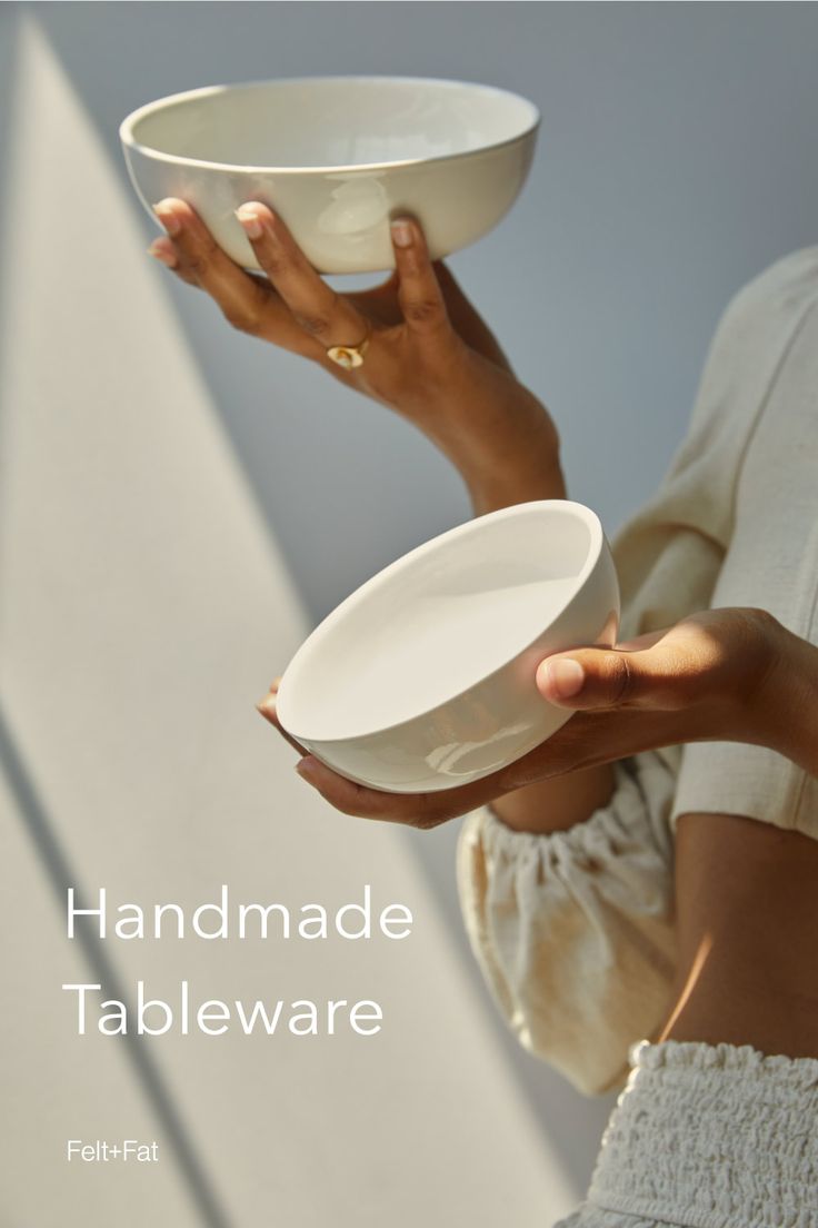 a woman holding a white bowl in her hand with the words handmade tableware below it