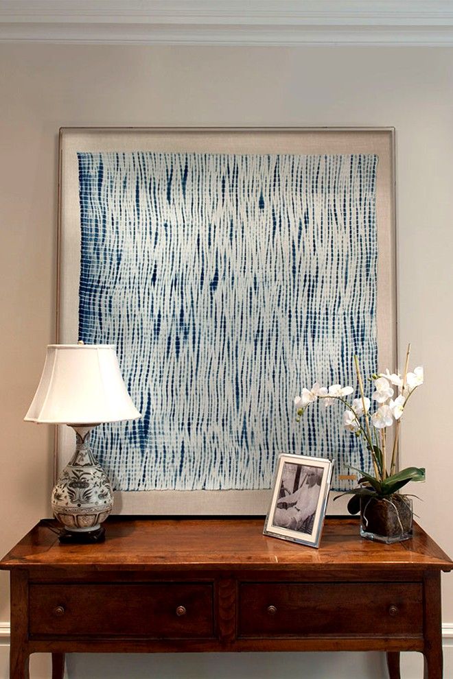 a wooden table topped with a lamp next to a blue and white painting on the wall