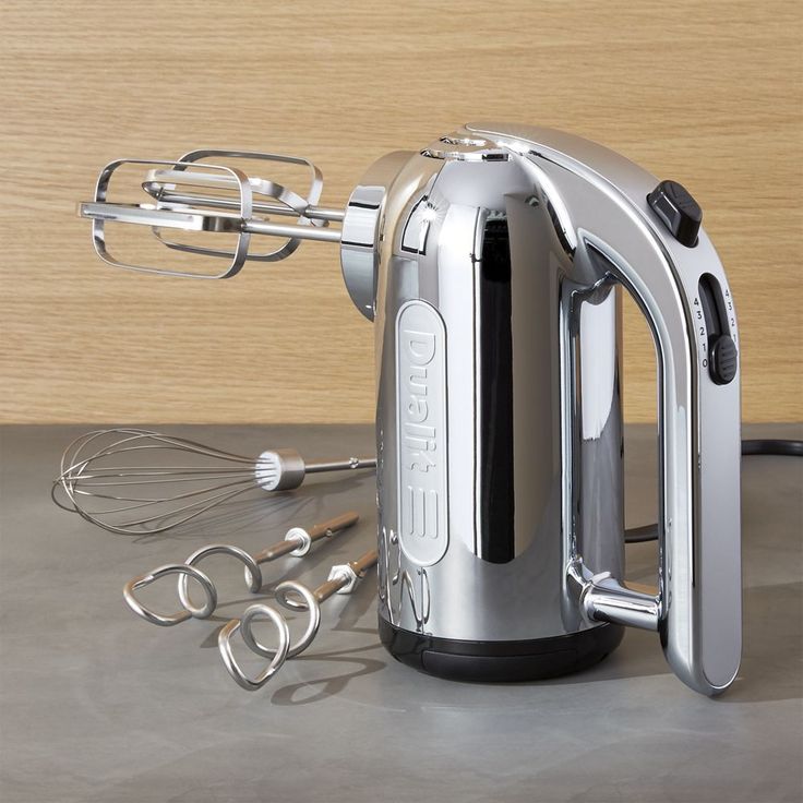 a silver electric mixer sitting on top of a counter next to kitchen utensils