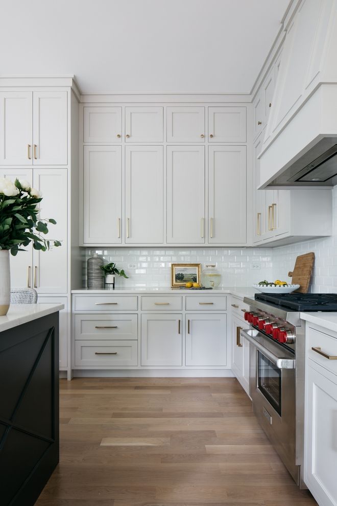 a kitchen with white cabinets and wood floors