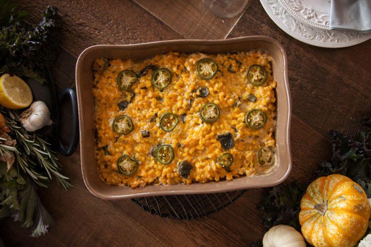 a casserole dish on a table with squash and pumpkins around the bowl