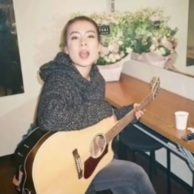 a woman sitting at a table with a guitar in front of her and looking surprised