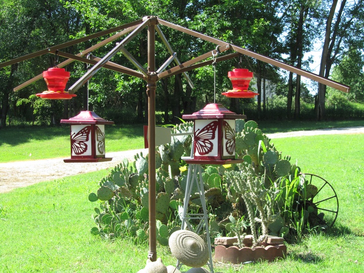 two red and white bird feeders sitting on top of a green field