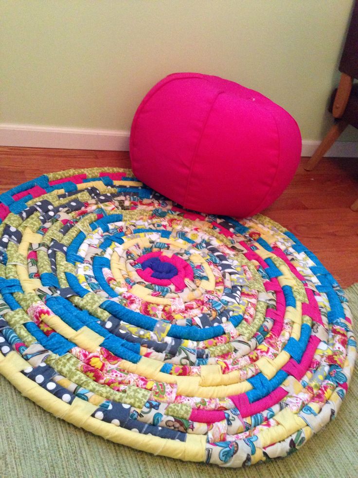 a round rug on the floor next to a pink pillow