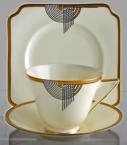 a white and gold dinner set with two cups, saucers and plates on it