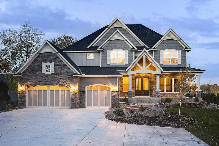 a large house with two garages and lights on the front door is lit up at night