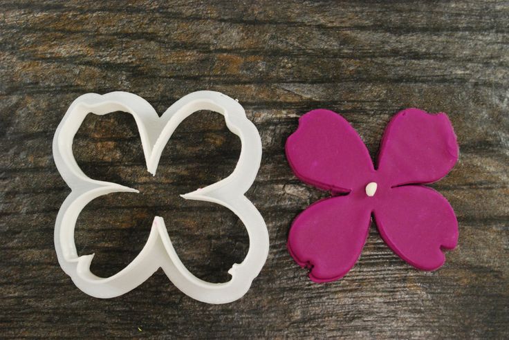 two flower shaped cookie cutters sitting on top of a wooden table next to each other