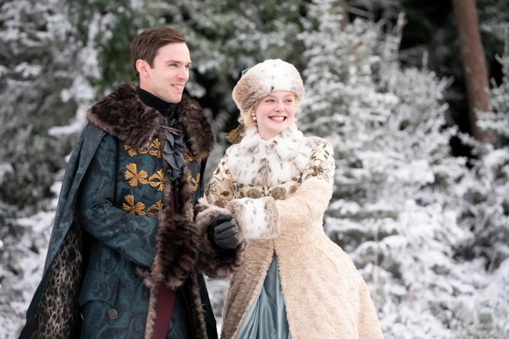 a man and woman dressed in period costumes walking through the snow