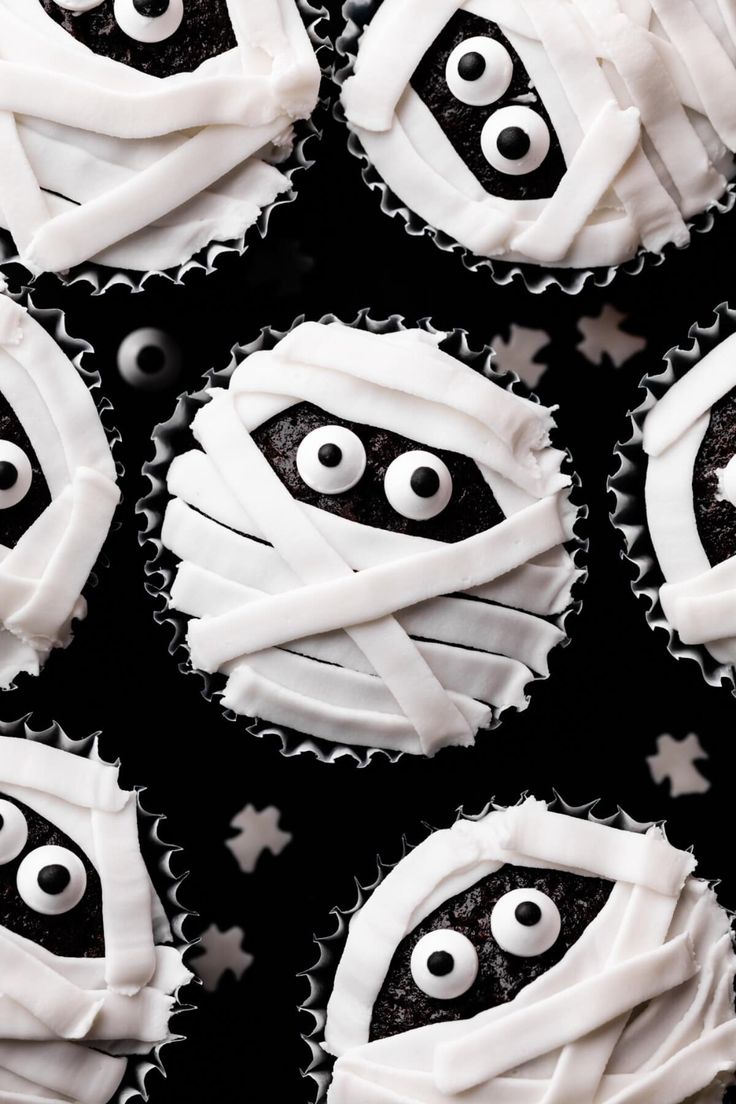 cupcakes with white frosting and black icing decorated to look like ghost faces