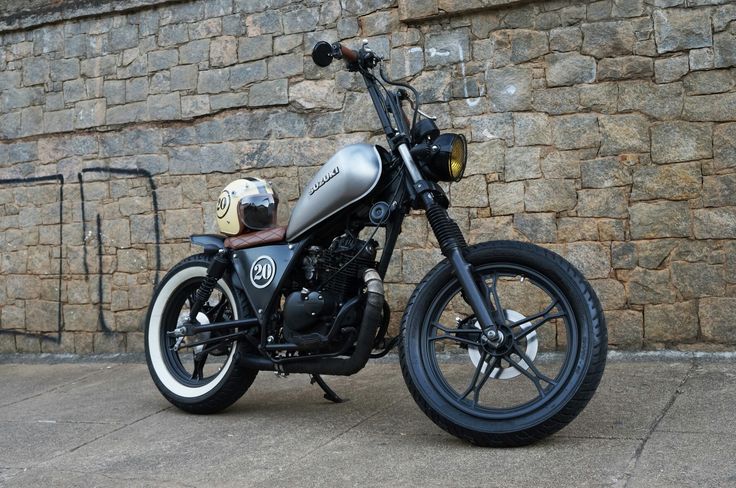 a motorcycle parked in front of a brick wall with a helmet on it's seat