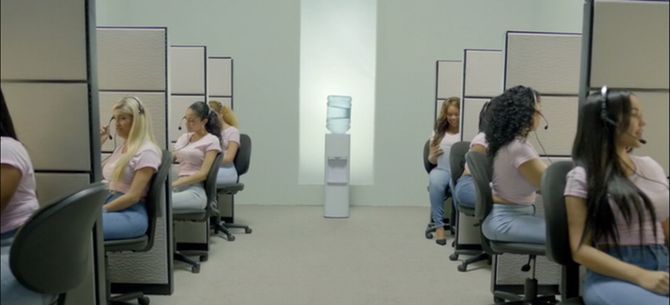 a group of women sitting in front of computer screens on desks with their heads turned to the side